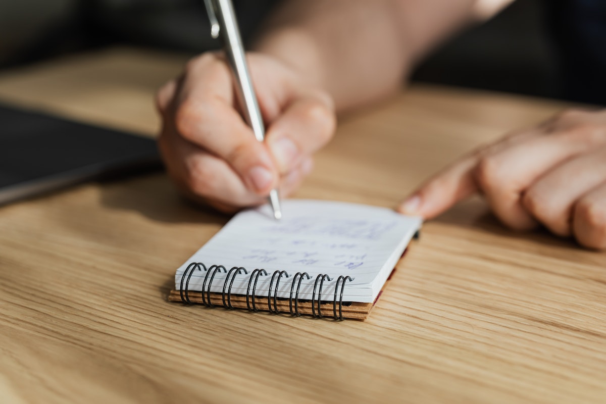 Uma pessoa fazendo uma anotação em um bloco de notas com caneta