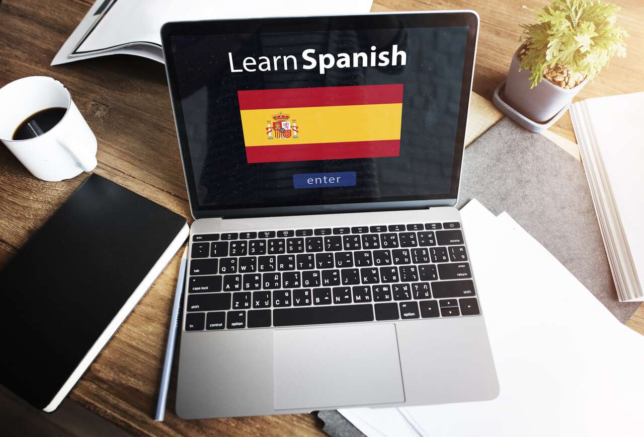 Notebook aberto com uma bandeira da Espanho escrito aprender espanhol 