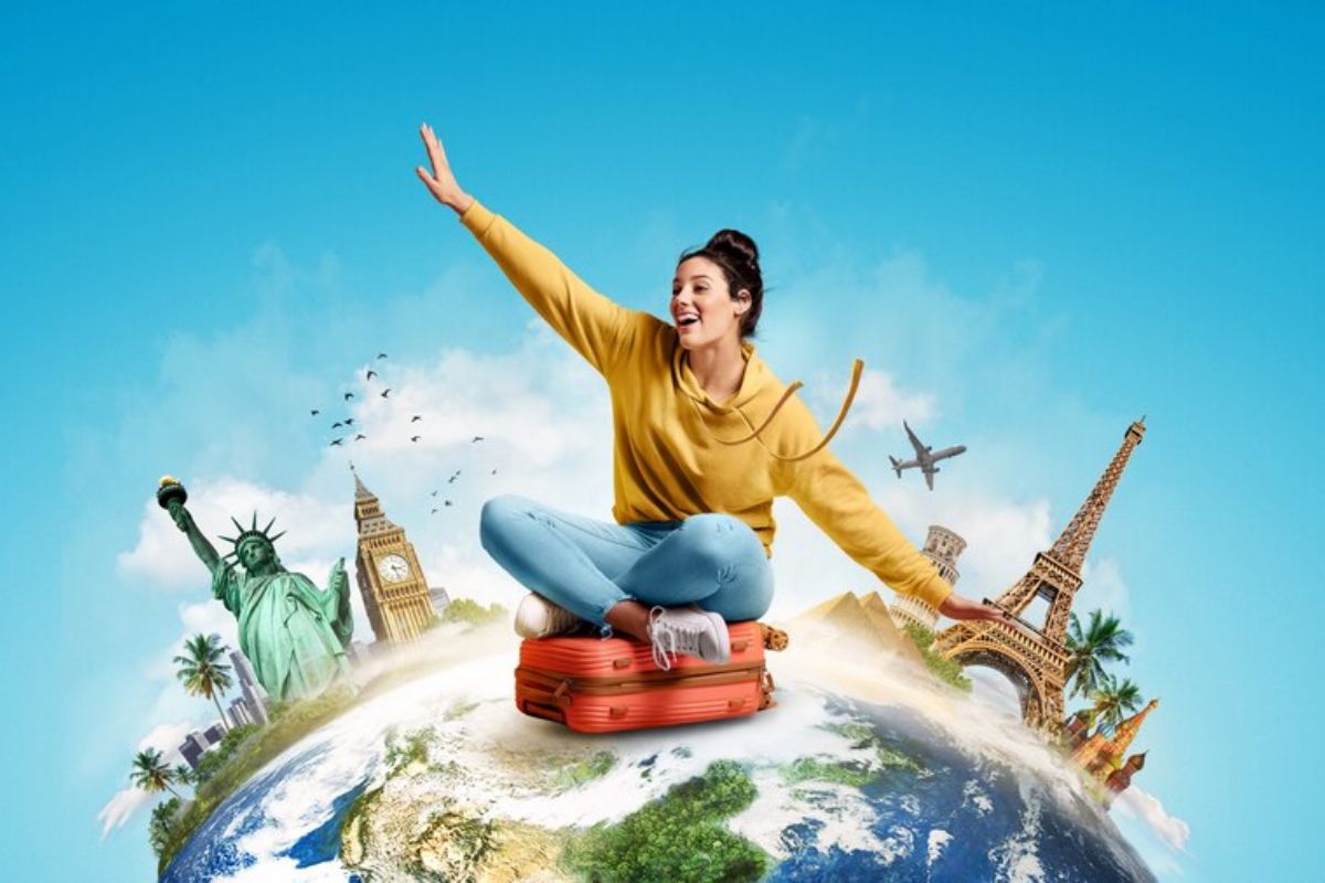Uma estudante sentada em cima da sua mala. Ela está "em cima do mundo" enquanto imagina seu Intercâmbio na Inglaterra 2024