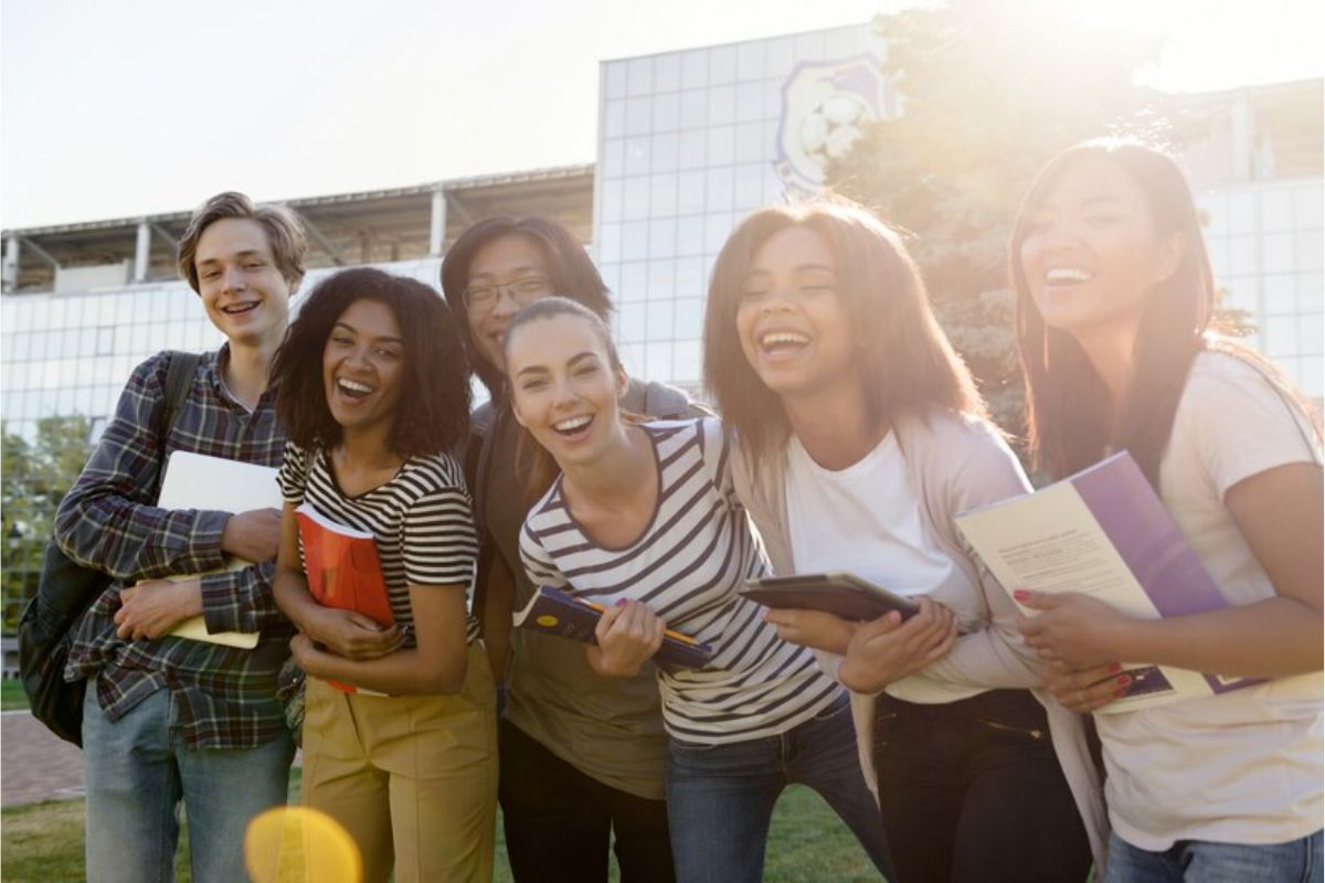 Um grupo de estudantes sorrindo, tirando foto juntos ao ar livre