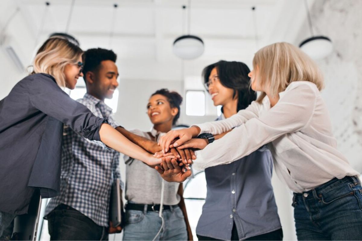 Um grupo de pessoas no escritório tocando as mãos juntos