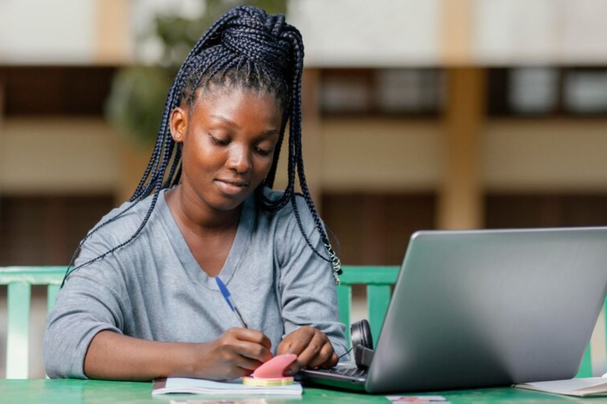 Uma aluna estuda ao ar livre e em seu notebook acessa o SISU 2025