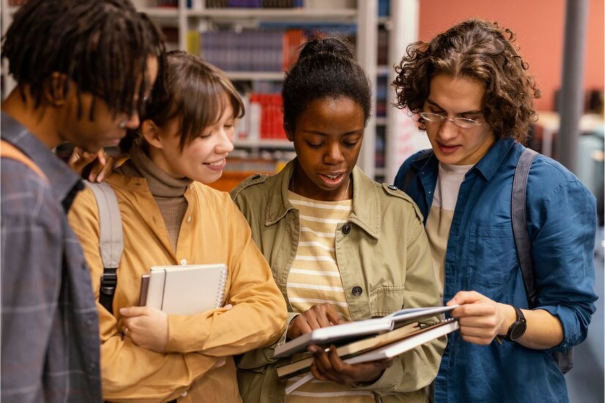 Quatro alunos de pé. Uma aluna mostra informações no tablet sobre o Aditamento FIES 2025