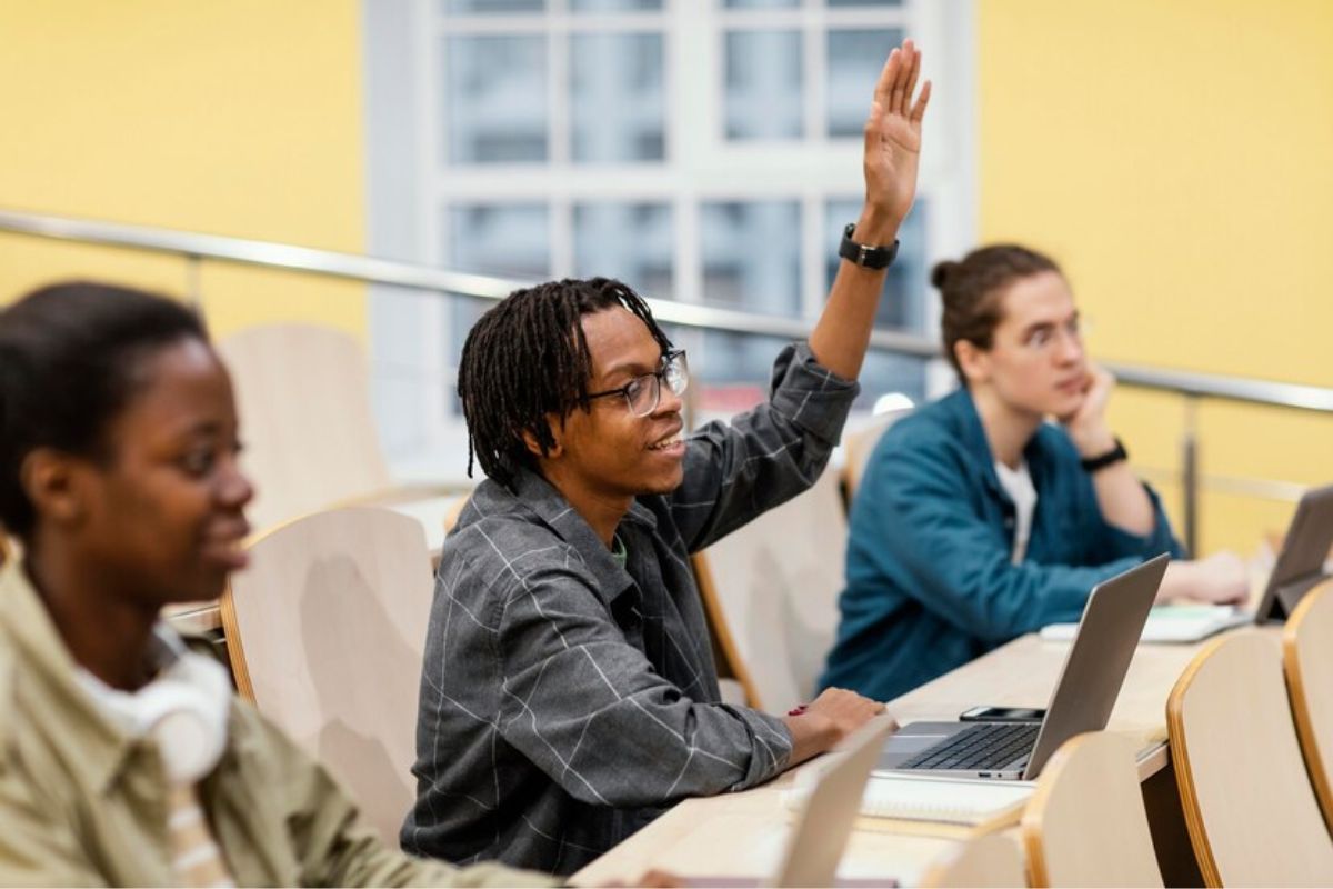 Um aluno na sala de aula levanta a mão para fazer um questionamento sobre o Aditamento FIES 2025
