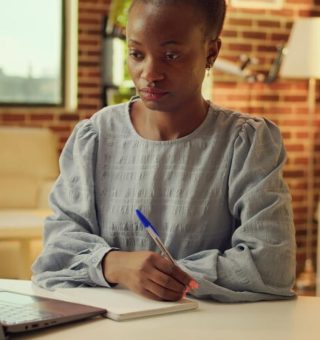 Uma estudante na biblioteca olha para o notebook com o braço apoiado na mesa enquanto confere Como Funciona o SISU 2025 em um notebook