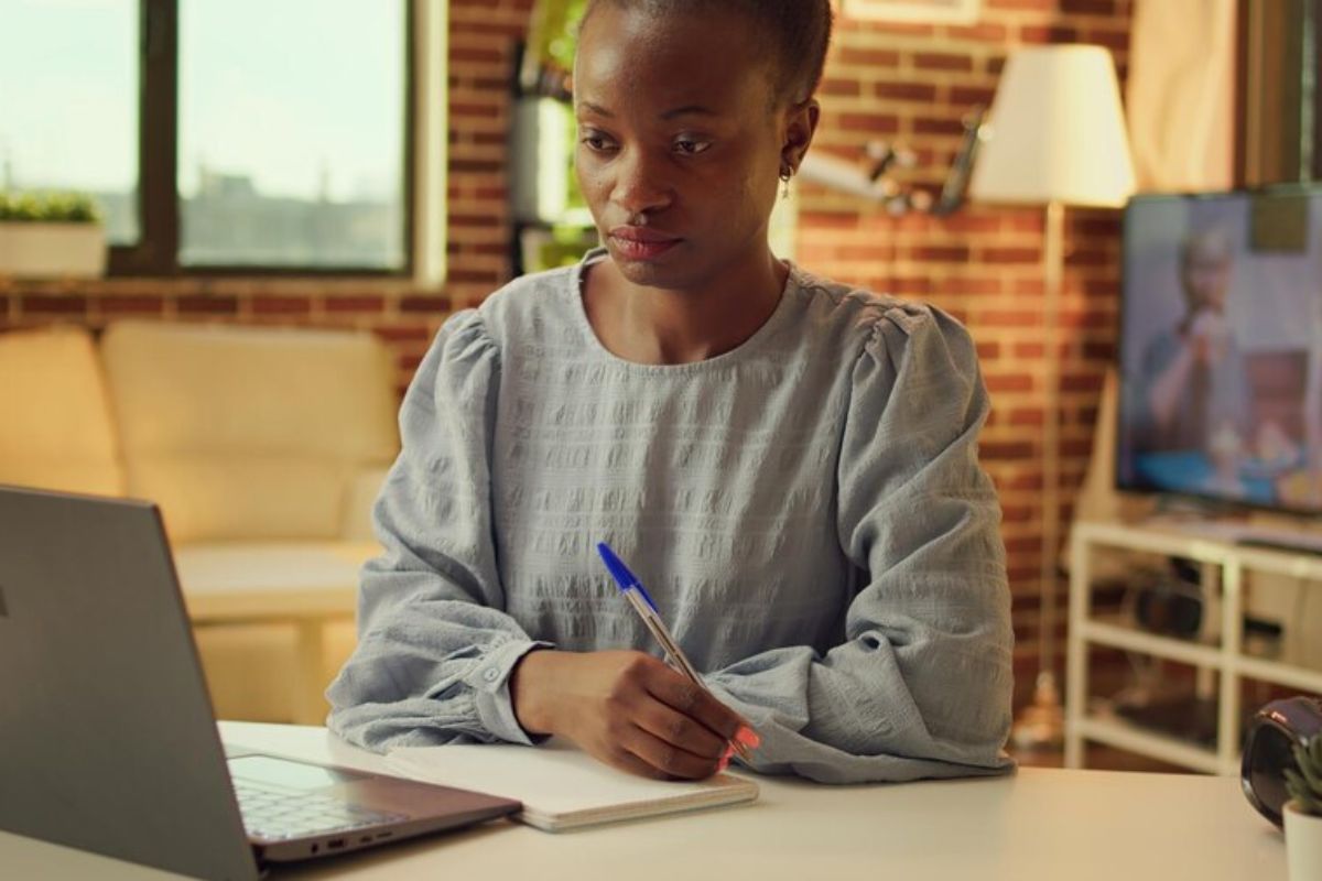 Uma estudante na biblioteca olha para o notebook com o braço apoiado na mesa enquanto confere Como Funciona o SISU 2025 em um notebook