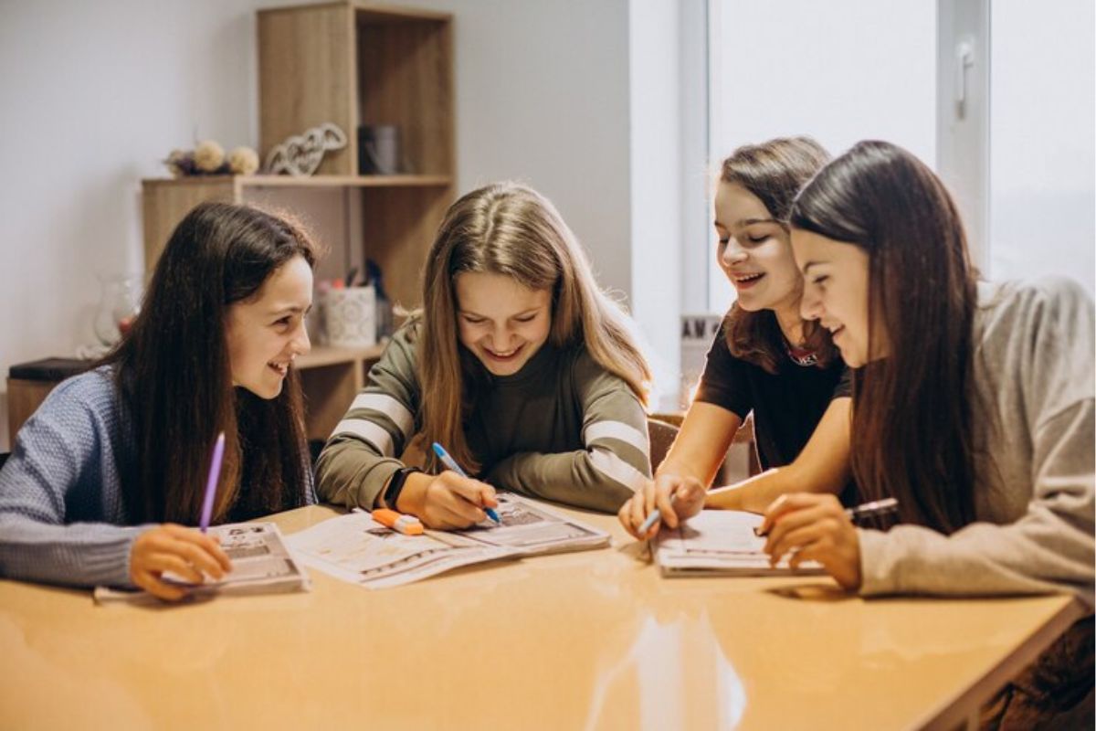 Um grupo de quatro alunas sentadas em torno da mesa enquanto buscam Calcular Nota do ENEM 2025