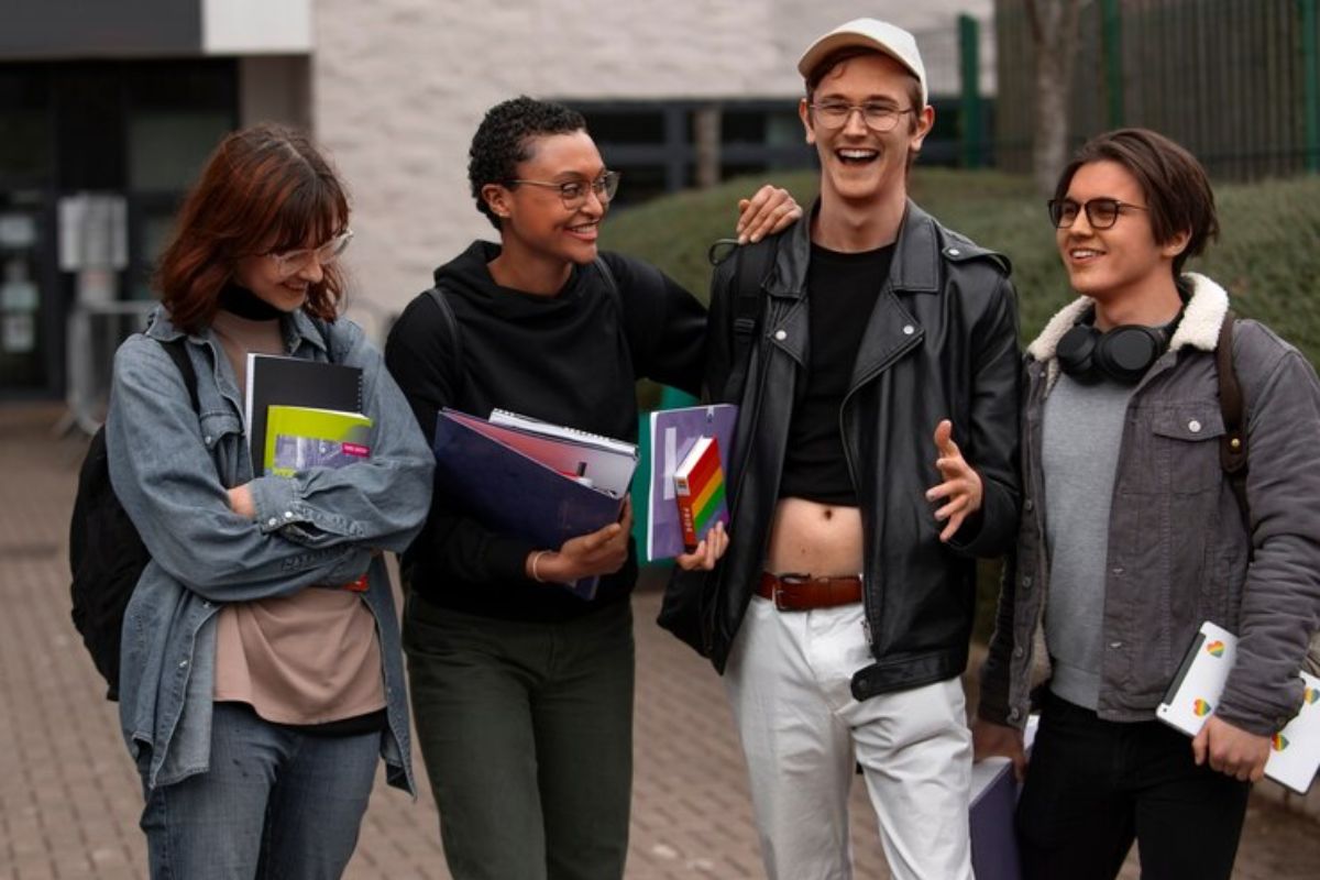 Quatro alunos andam com seus materiais no braço. Eles estão sorrindo após ver o Resultado do SISU 2025