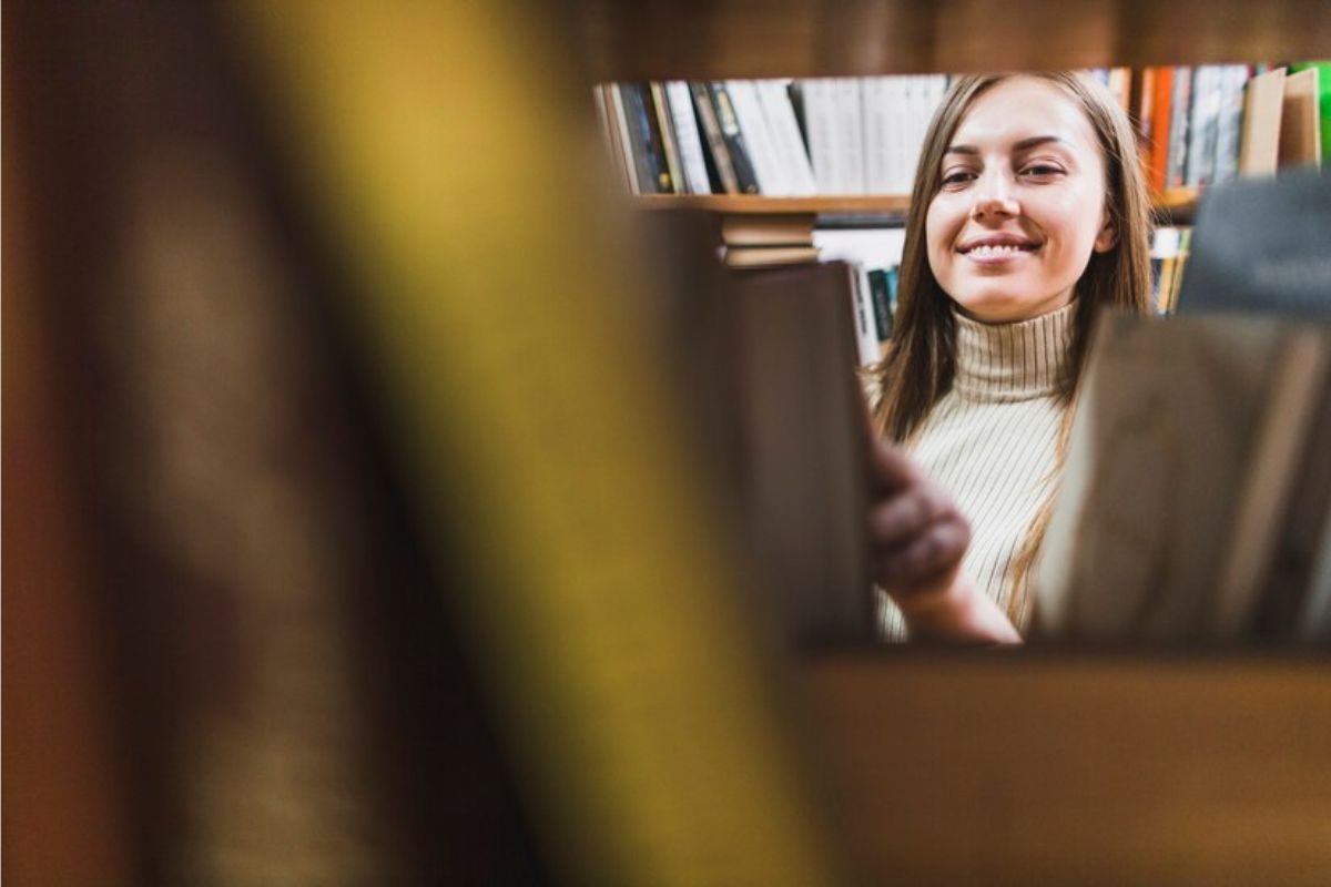 Uma aluna vista por meio de alguns livros na biblioteca