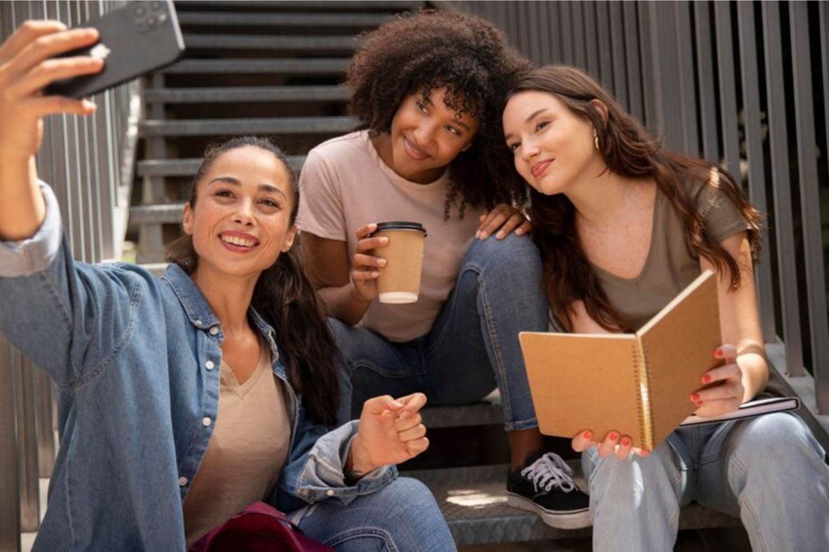 Um trio de alunas tirando selfie após se encontrarem para ver o Edital do ProUni 2025