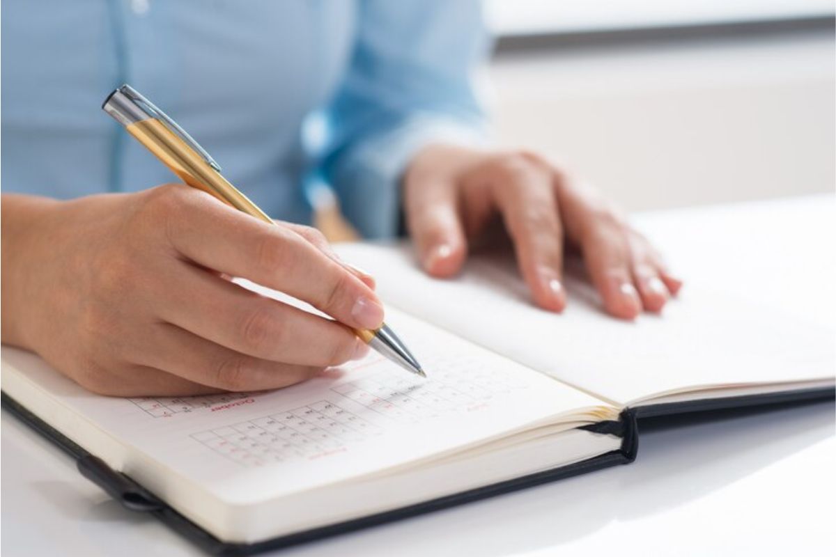 Uma pessoa faz anotações com a caneta em sua agenda sobre o Cronograma ProUni 2025