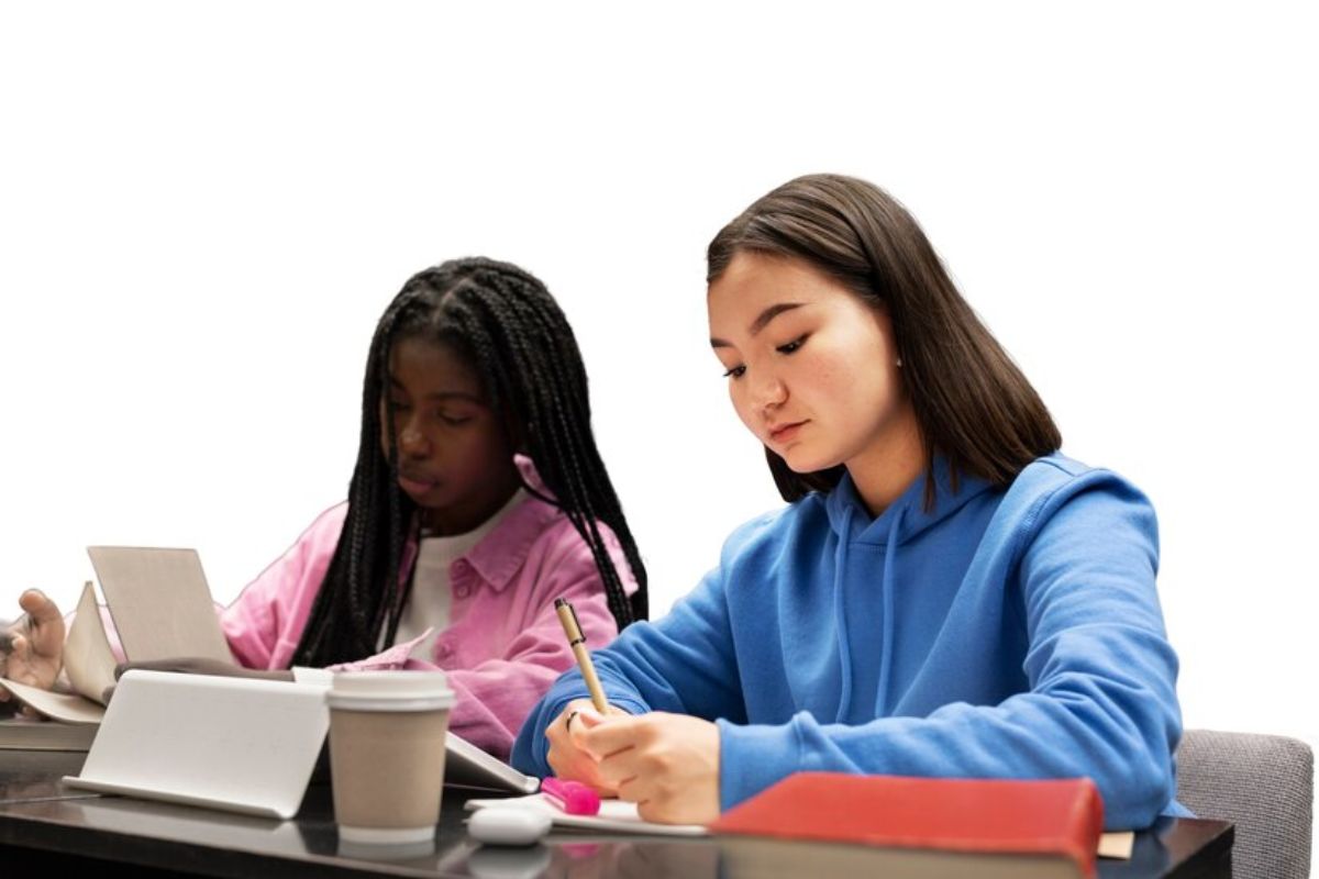 Duas alunas estudam juntas na sala de aula enquanto fazem anotações em seus cadernos