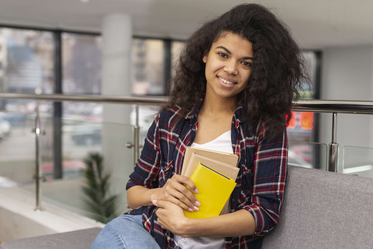 jovem estudante segurando cadernos sentada na biblioteca da universidade
