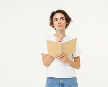 Uma aluna leva o lápis à boca e olha para o alto. Ela está com um livro aberto tem dúvidas quanto Classificação ProUni 2025