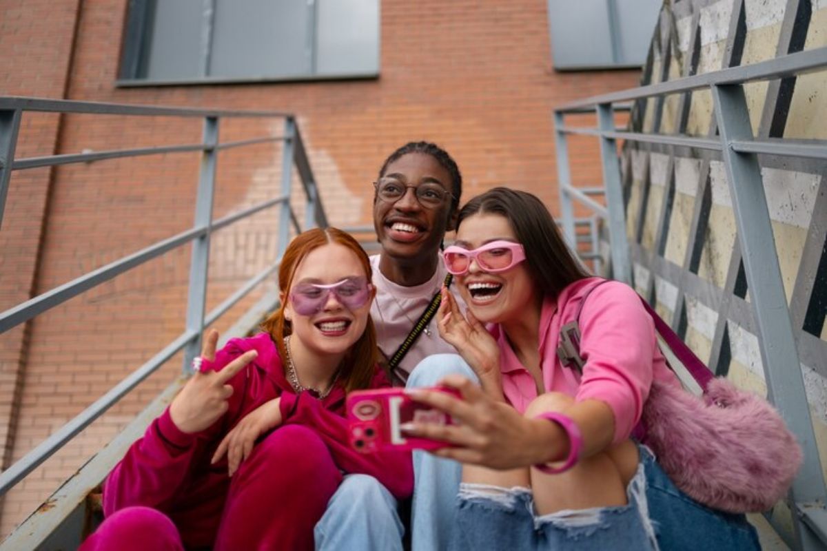 Três alunas de rosa tiram foto na escada da universidade após a aprovação no ProUni 2025 para Alunos de Escolas Particulares