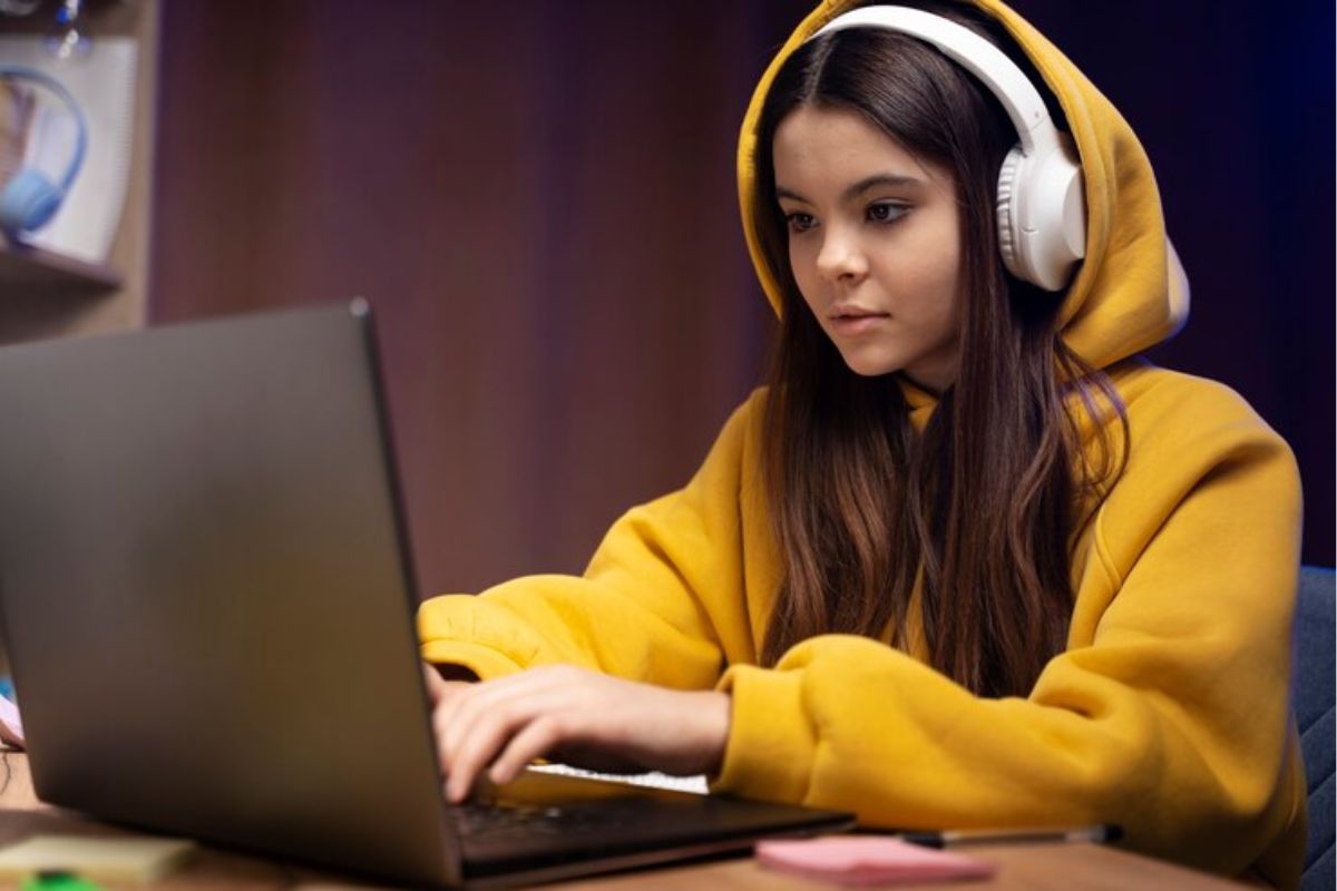 Uma jovem de moletom amarelo enquanto mexe em seu notebook olhando o Site PROUNI 2025