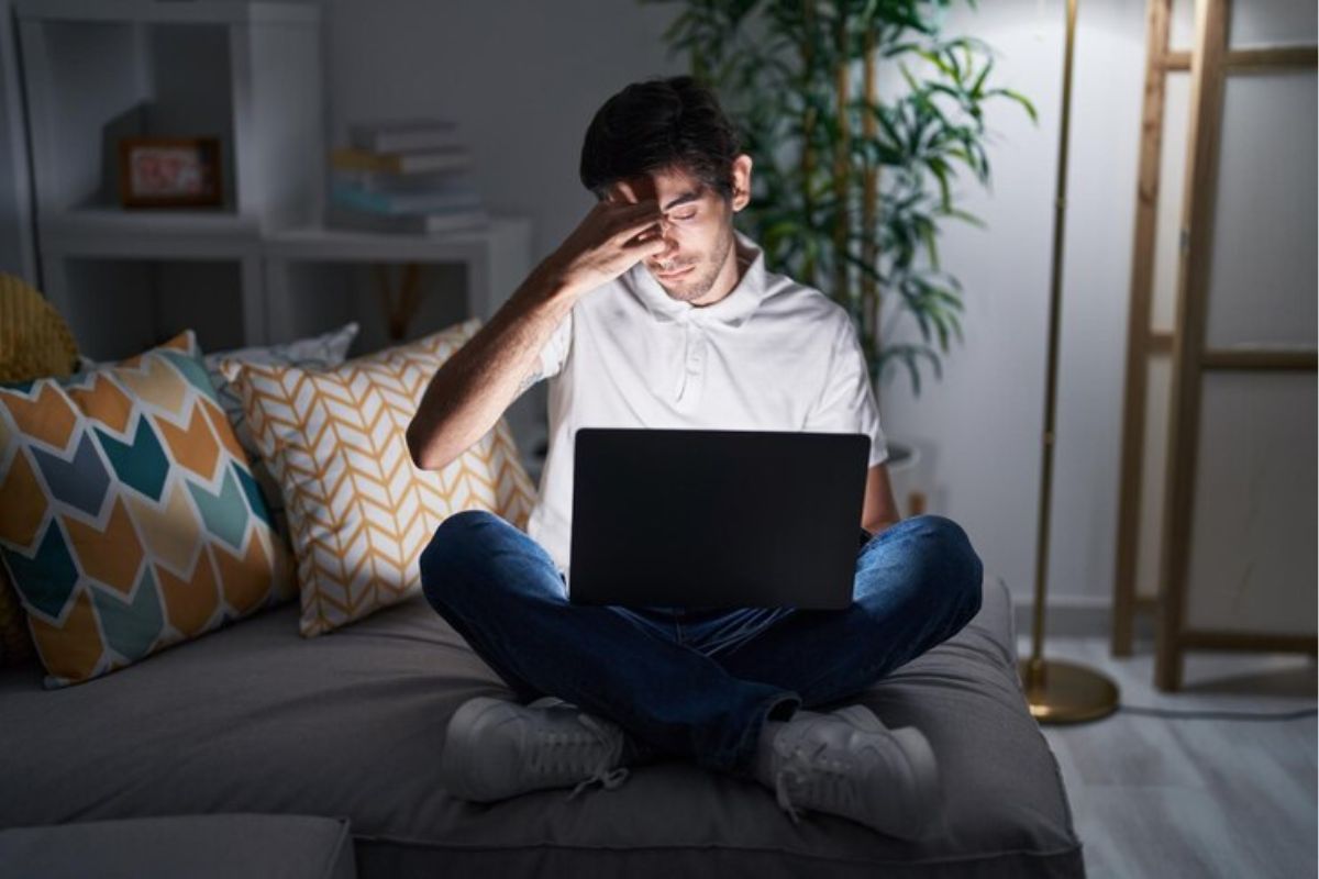 Um jovem vê Como Estudar para o ENEM 2025. Ele está em seu quarto com as luzes apagadas e o notebook no colo