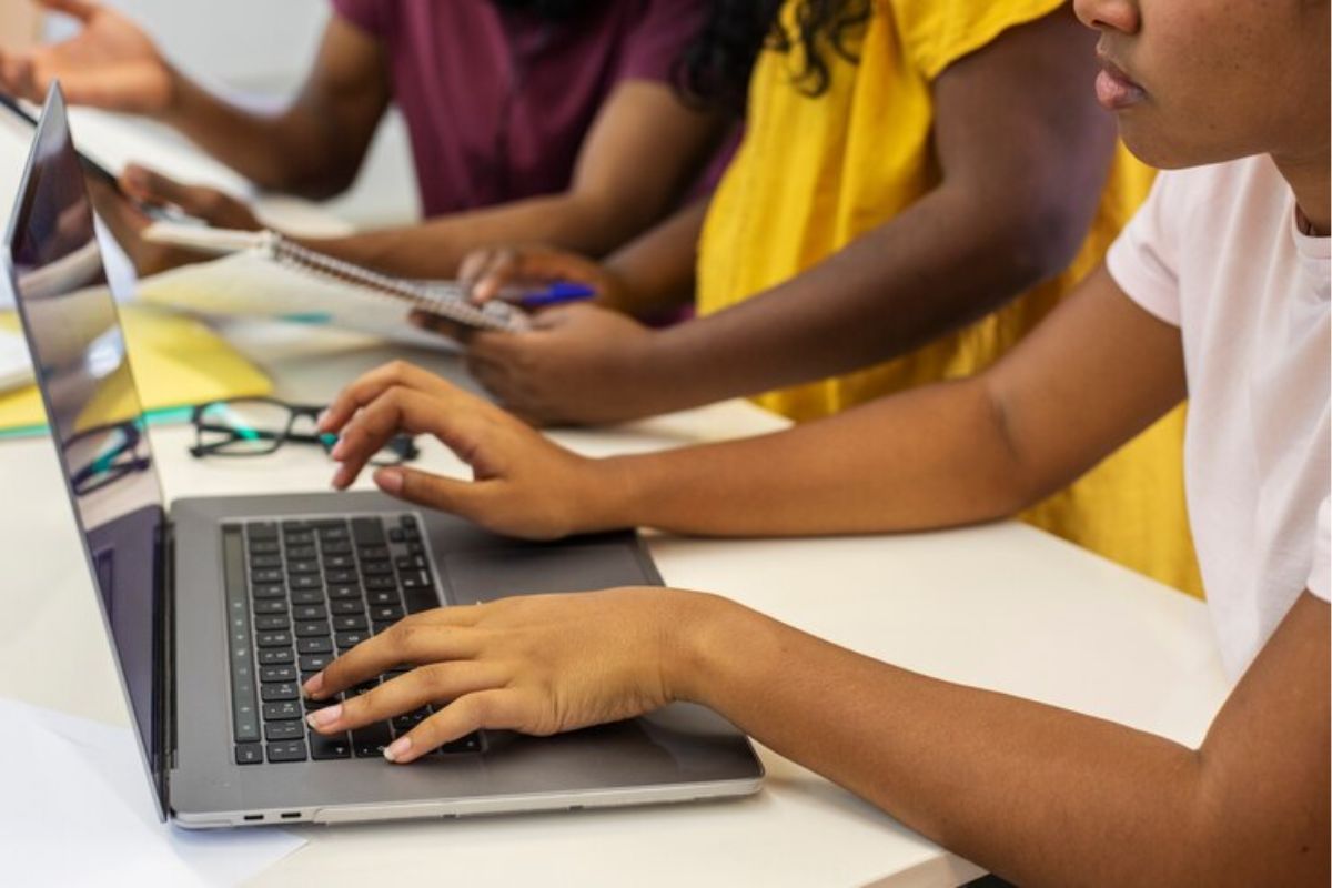 Três estudantes na sala de informática usam o computador para participar das Inscrições ETEC 2025