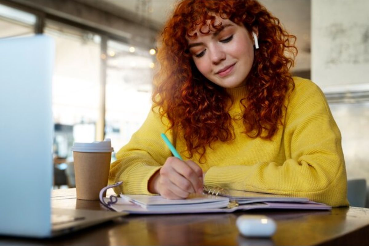 Uma menina de blusa de frio amarela está fazendo anotações em seu caderno