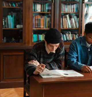 Dois alunos estão sentados estudando para Química no ENEM 2025 com livros abertos na mesa