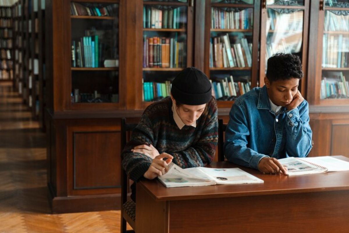 Dois alunos estão sentados estudando para Química no ENEM 2025 com livros abertos na mesa