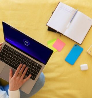 Uma pessoa sentada na cama usa um notebook no colo para acessar o Simulador PROUNI 2025