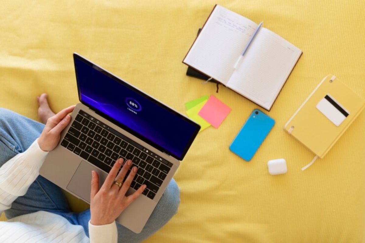 Uma pessoa sentada na cama usa um notebook no colo para acessar o Simulador PROUNI 2025