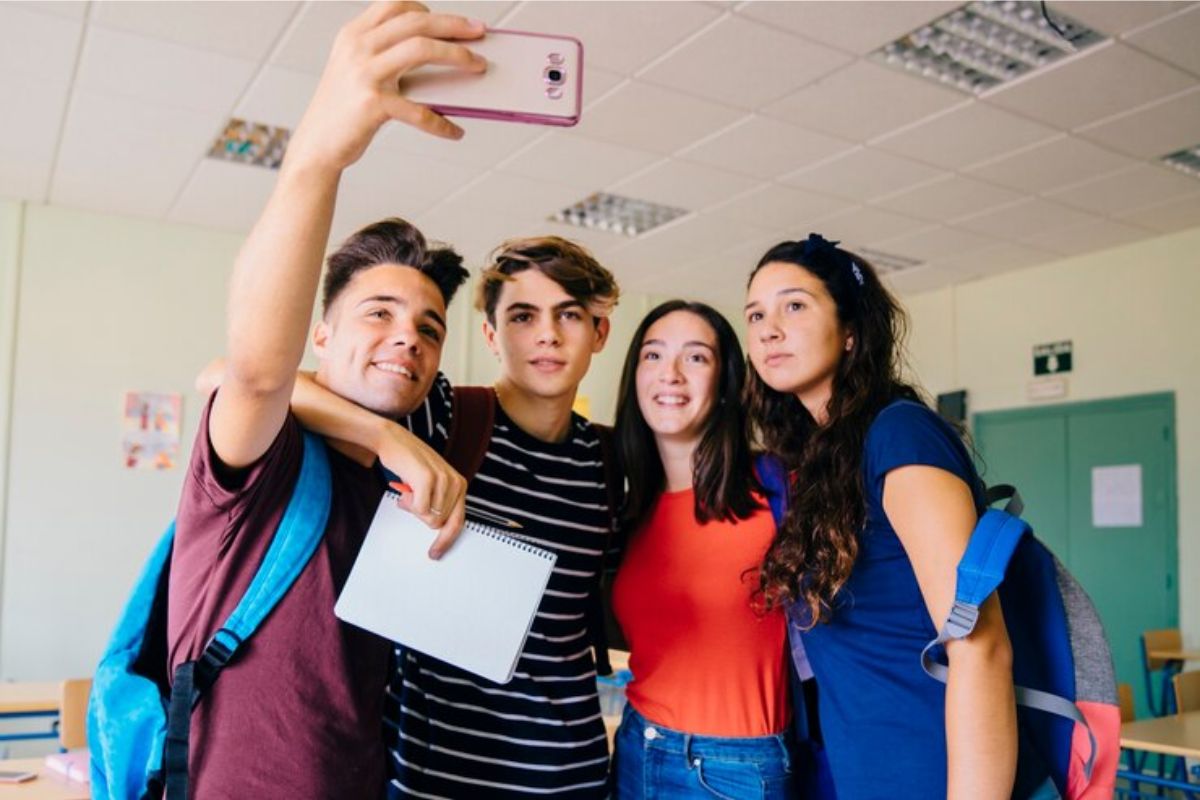 Um grupo de quatro alunos tira uma selfie dentro da sala de aula