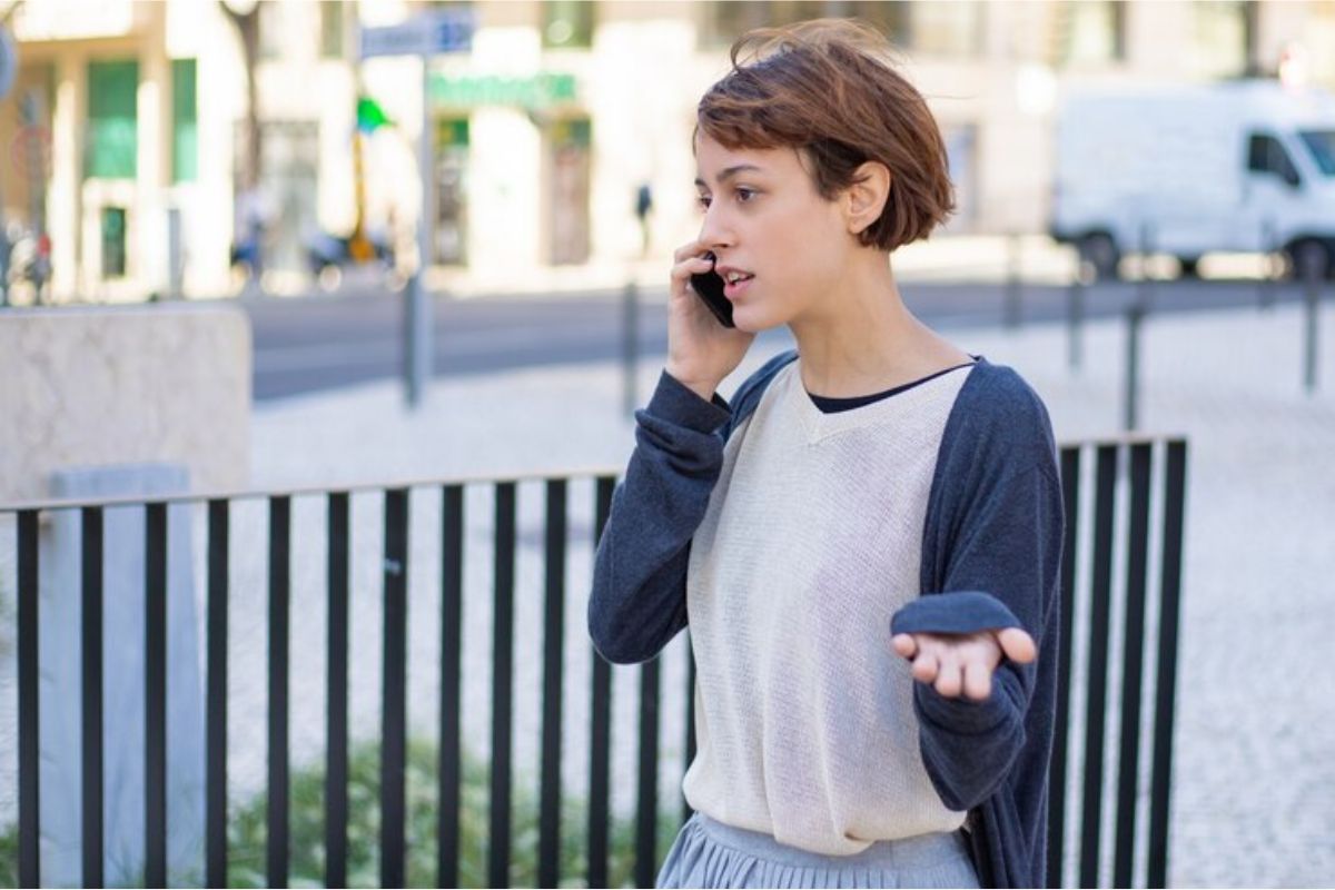 Uma menina na rua falando no celular, ligando para o Telefone ETEC 2025