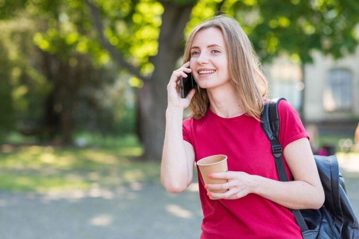 Uma menina no bosque da escola falando no celular com o Telefone ETEC 2025