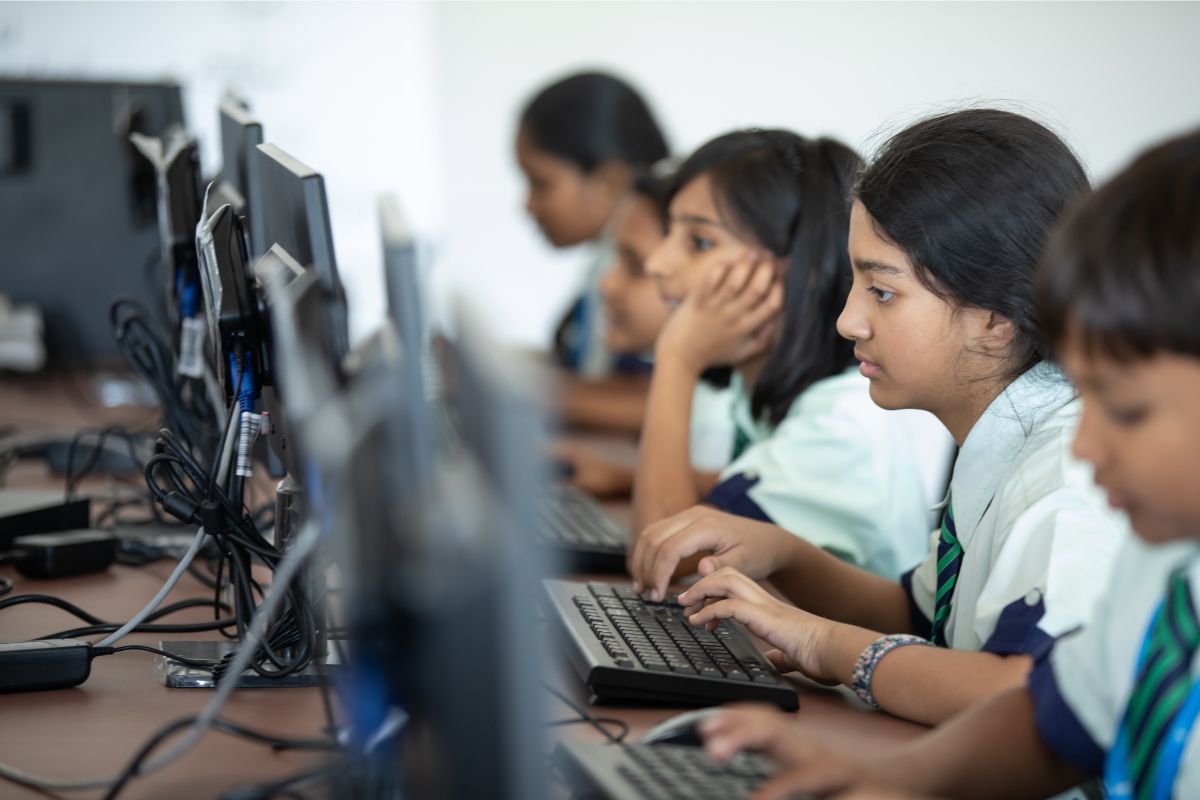 um grupo de estudantes em frente ao computador na sede da Universidade do Trabalho Digital