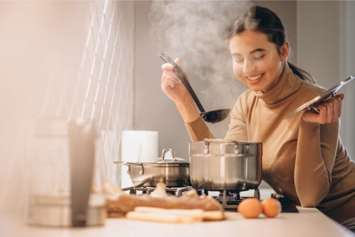 Uma mulher em frente ao fogão segura uma concha de feijão ─ aprenda a cozinhar