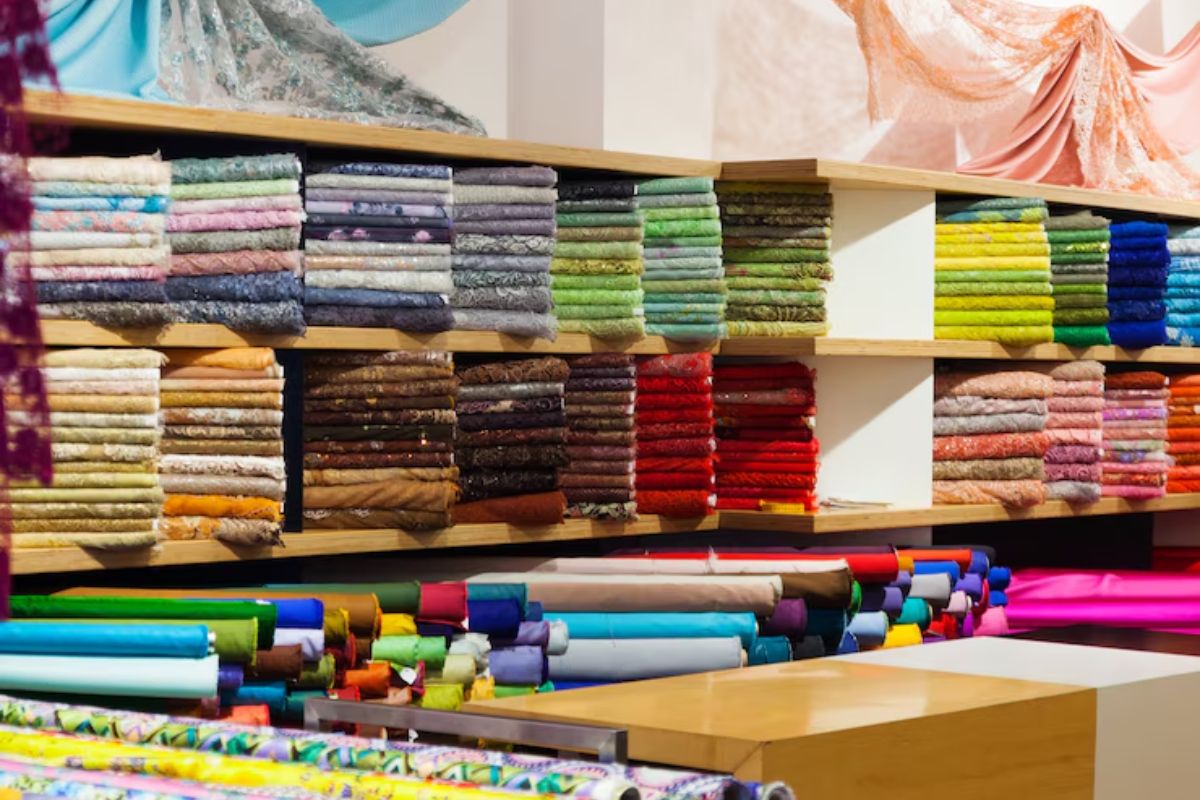 O interior de uma loja de tecidos com diversas opções e cores de produtos em prateleiras