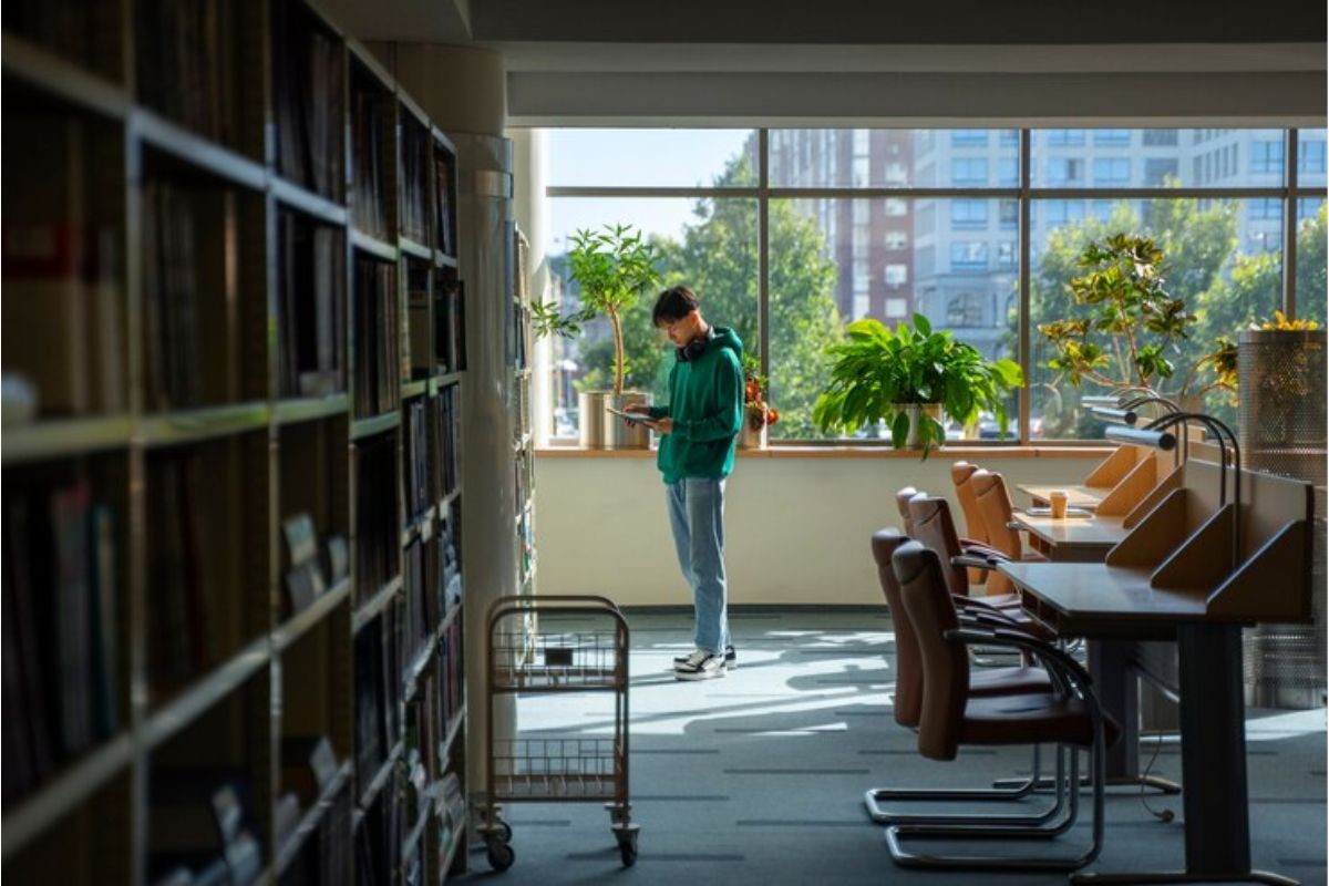 Um estudante no fundo da sala de uma biblioteca vazia