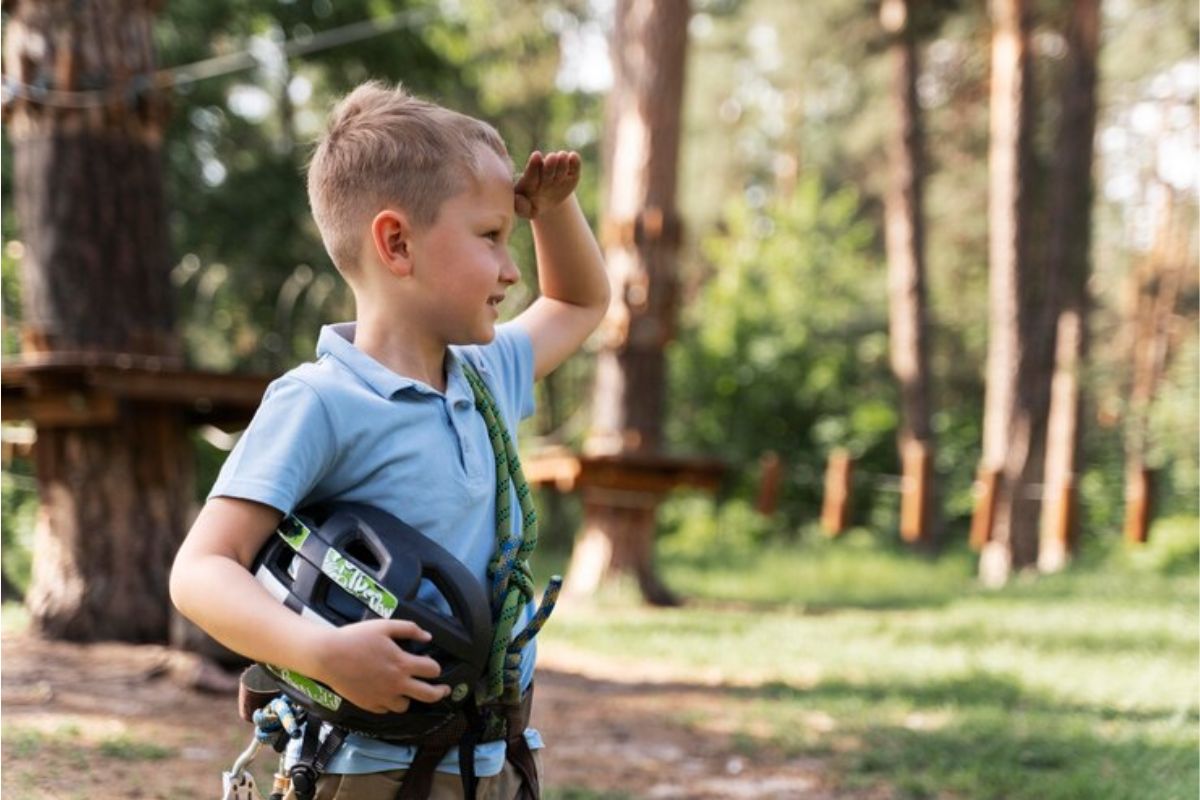Um pequeno estudante em um bosque com um capacete na mão