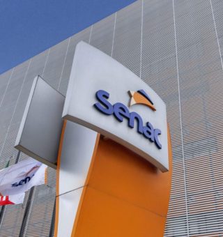 Imagem de uma entrada do SENAC com a placa da instituição em frente ao prédio