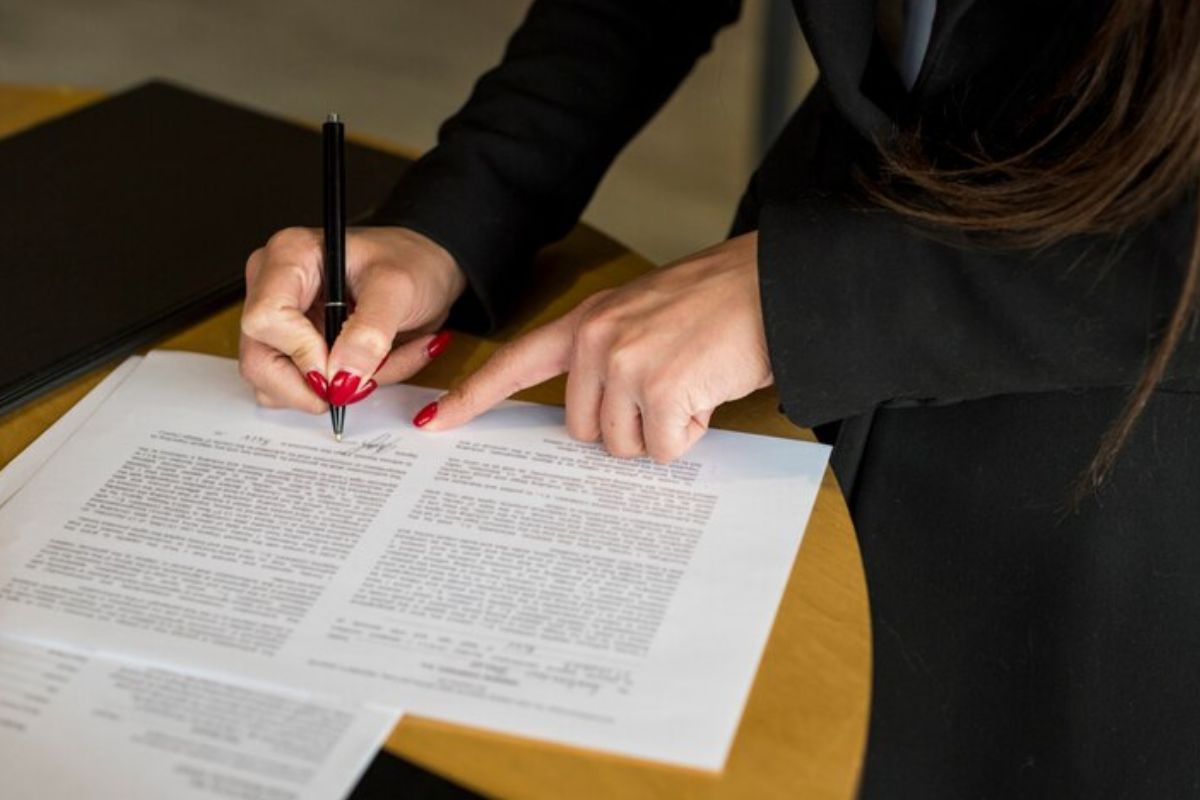 Uma estudante de direito lendo um documento na mesa referente ao curso de Perito Criminal 2024