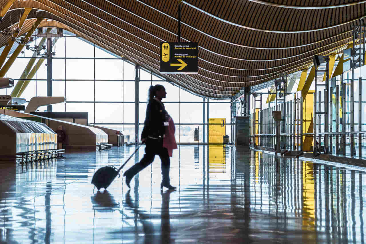 Jovem carregando a mal atravessando o portão no aeroporto 