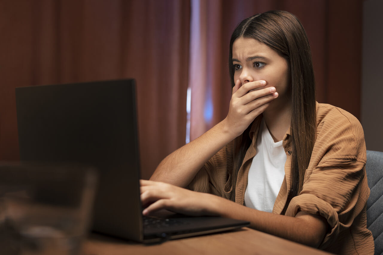 Jovem expressa preocupação olhando para algo no notebook 