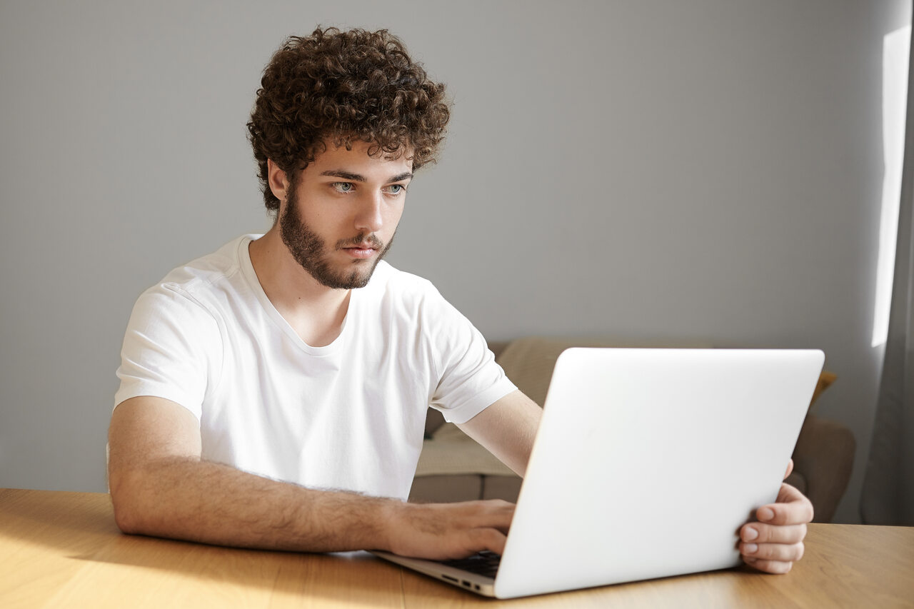 Jovem olha para o notebook com expressão atenta 