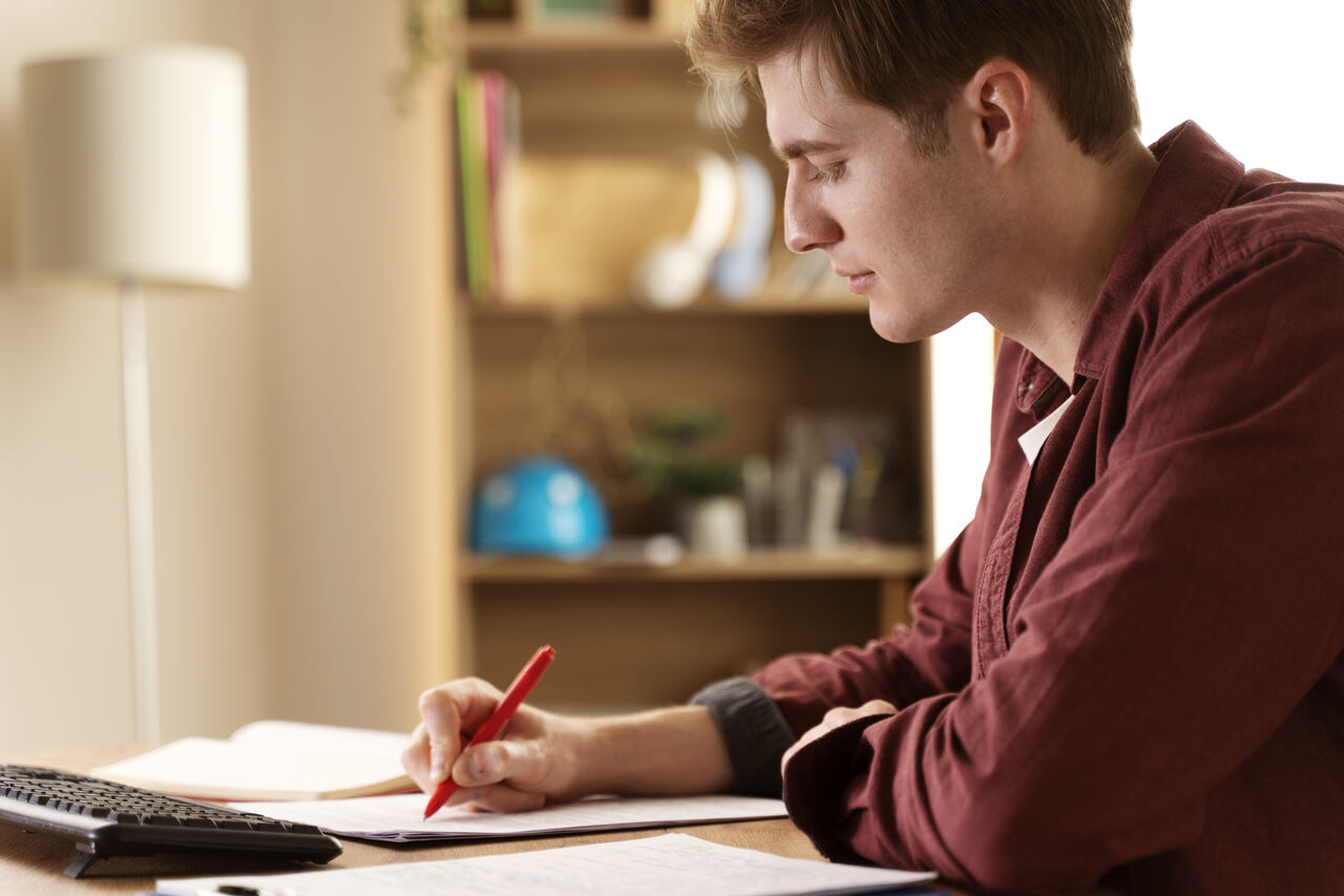 Jovem faz anotações enquanto estuda
